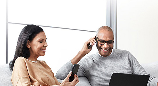 couple on sofa with phone and laptop