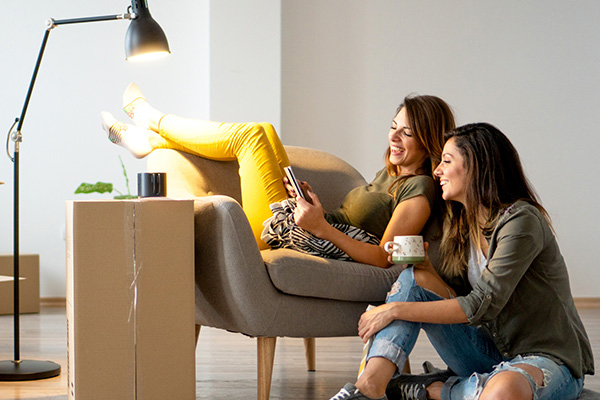 two girls one on the chair and another on the floor looking at a phone