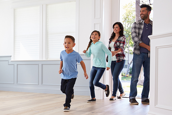 family of four with a boy and girl walking into a house