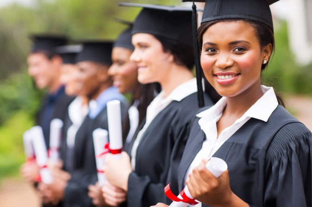 a girl holding her diploma and smiling at camera